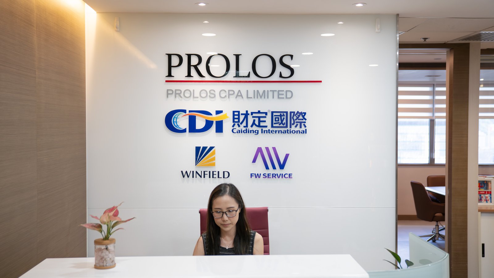 财定国际香港办公室前台，展示PROLOS会计师事务所、CDI财定国际等品牌标识